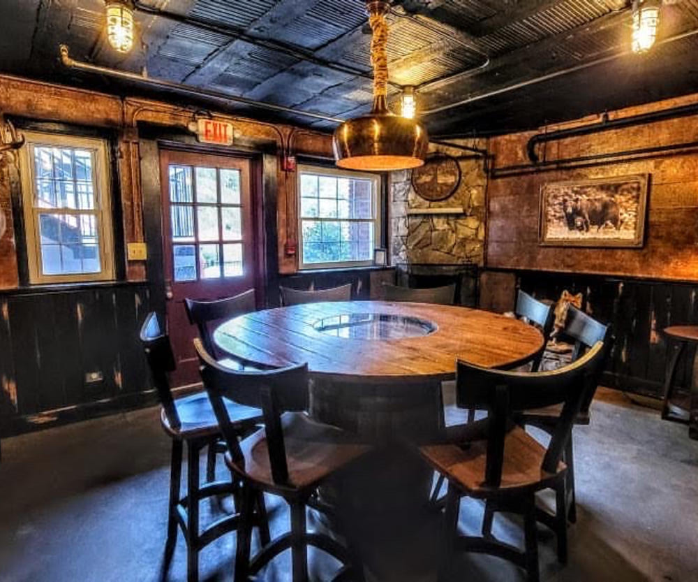 Round plank table ringed by chairs in a panelled room